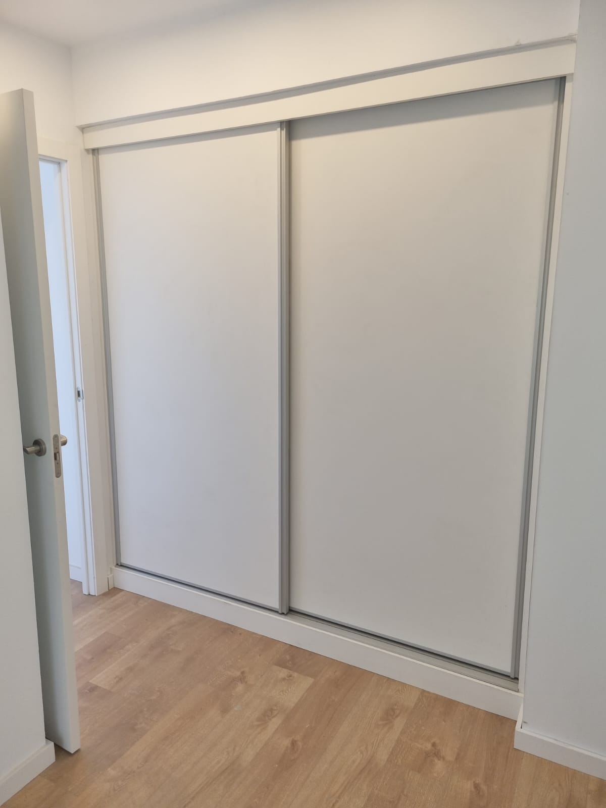 Armario blanco empotrado doble Armario empotrado blanco con puertas correderas con 3 cajones, estantes y percheros, vista en modo cerrado. Hecho a medida.