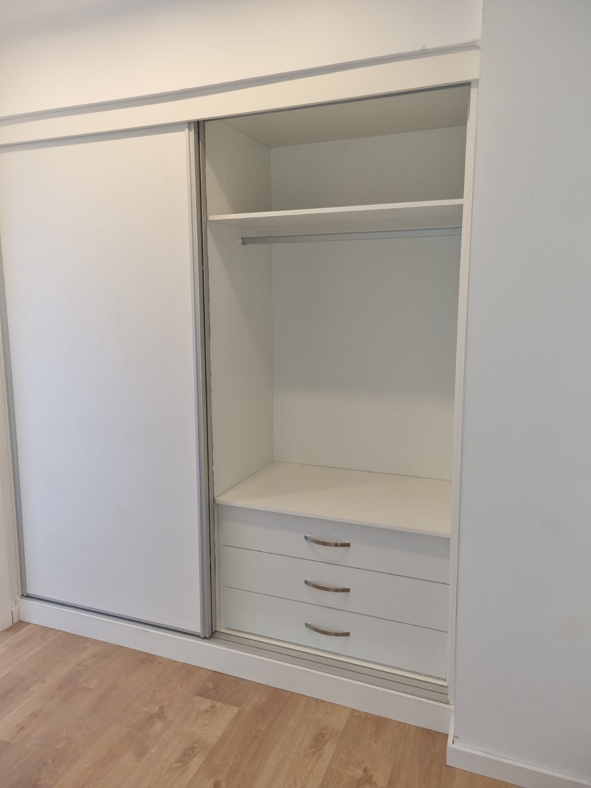 Armario empotrado blanco, doble. Armario empotrado blanco con puertas correderas con 3 cajones, estantes y percheros. Vistas desde el lado derecho. Hecho a medida.